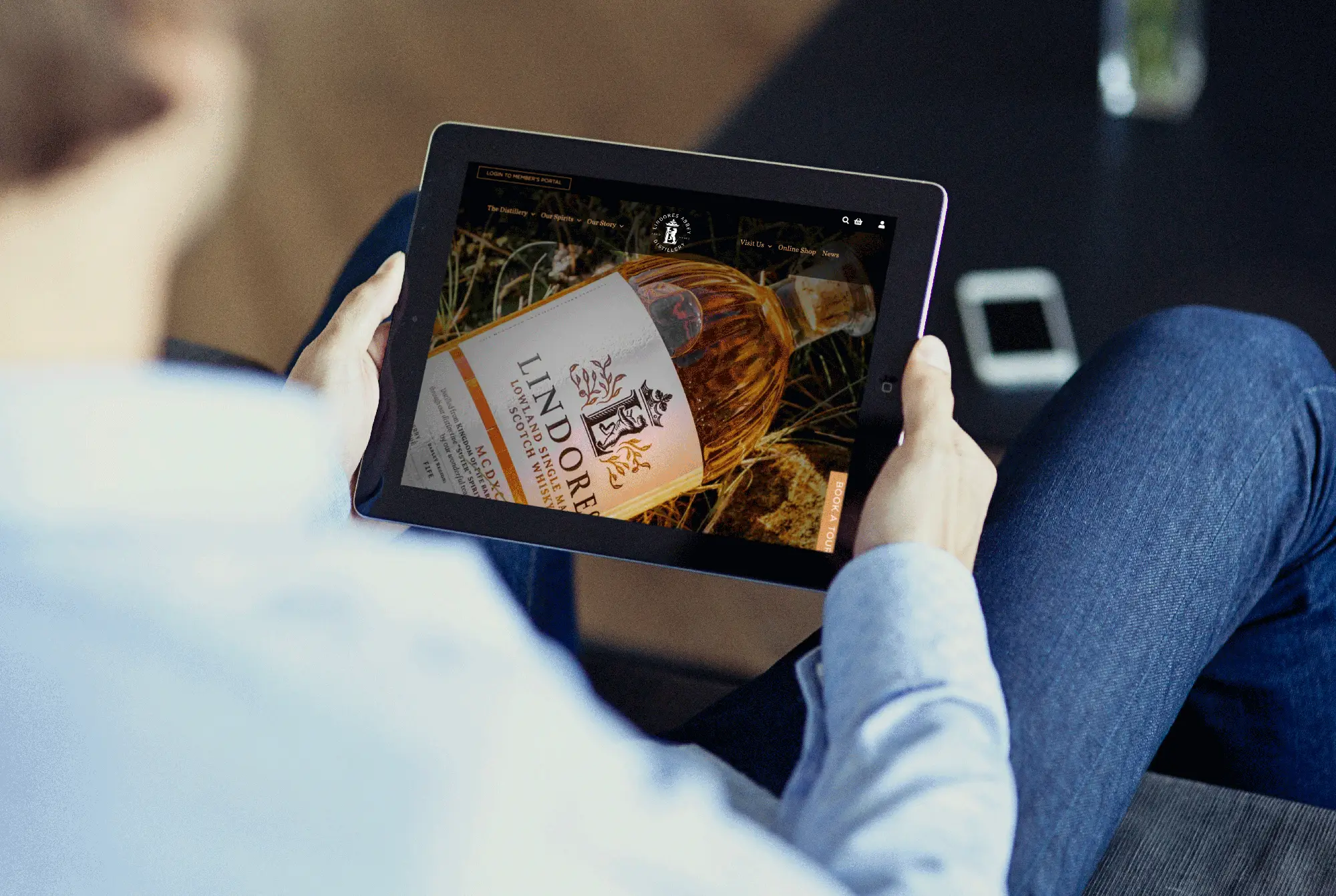 Person holding a tablet displaying a whisky product page on the Lindores Abbey Distillery website